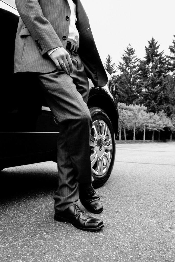 Man in suit leaning against a car