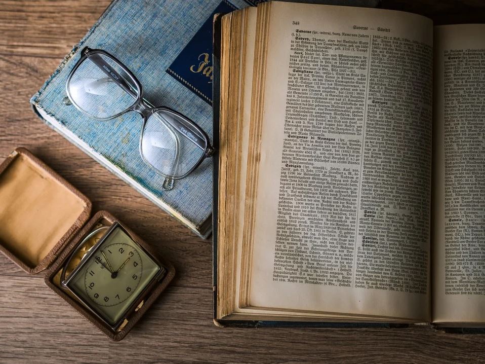 Old book with glasses and clock