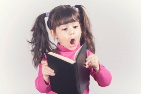 Little girl reading with surprise face