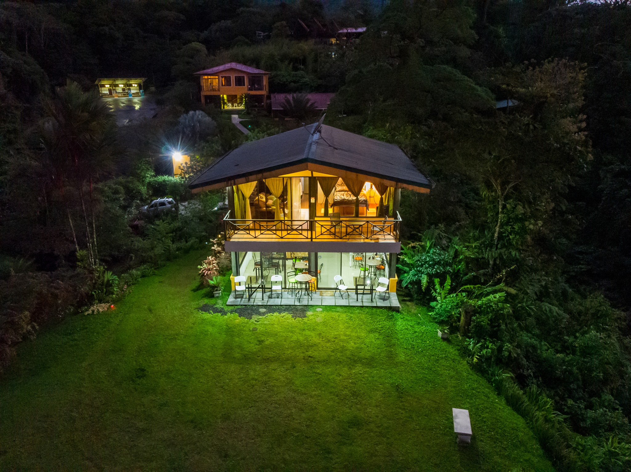 Nighttime aerial view of Arenal Garden Lodge surrounded by forest and glowing lights