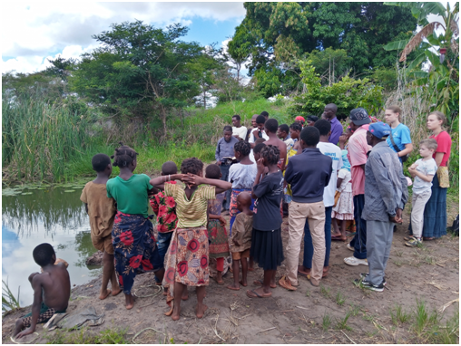 People gathering on a riverbank for baptisms