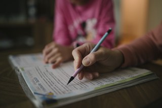 Educación en casa: un adulto guía a un niño en la mesa, en un colegio online Chile