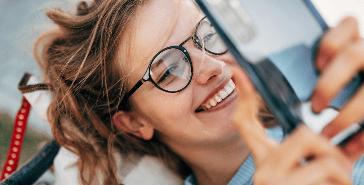 a girl smiling and looking to a phone
