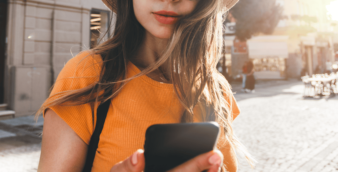 girl with an orange top looking to a phone
