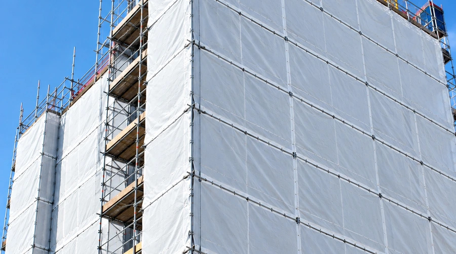 Fire-retardant tarpaulin sheeting enclosing scaffolding on a high-rise construction site