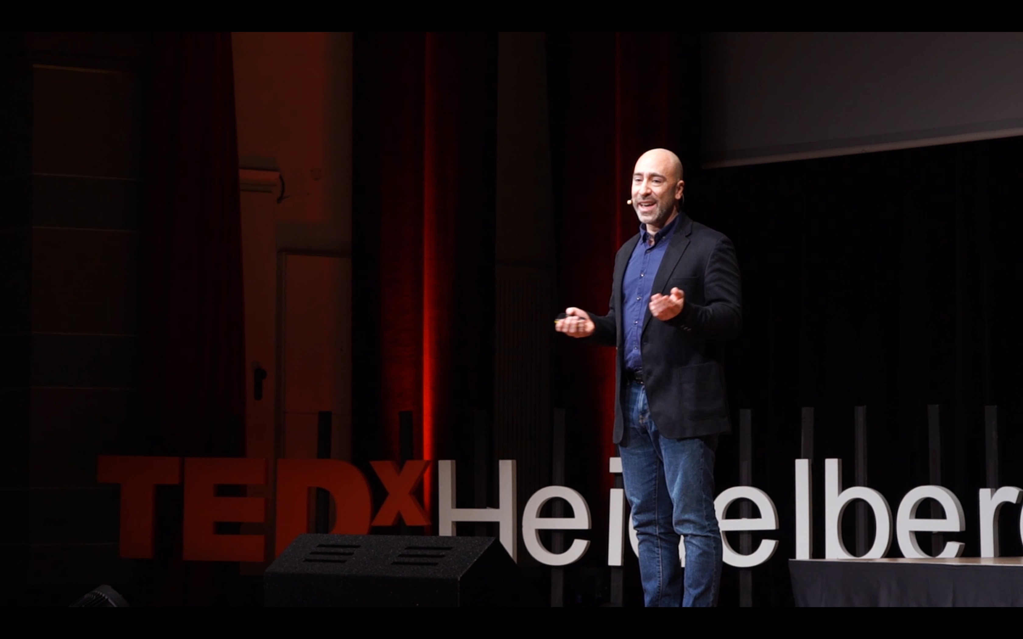 Marc onstage speaking about belonging abroad to a warm, attentive audience