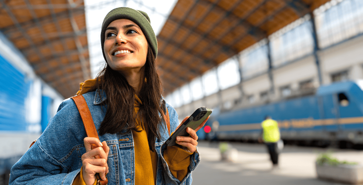 a girl holding a phone at a train station