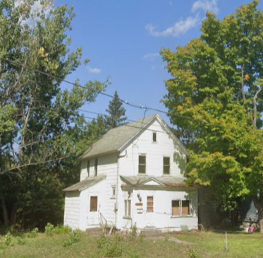Weathered two-story white house before renovation in Houghton, Michigan