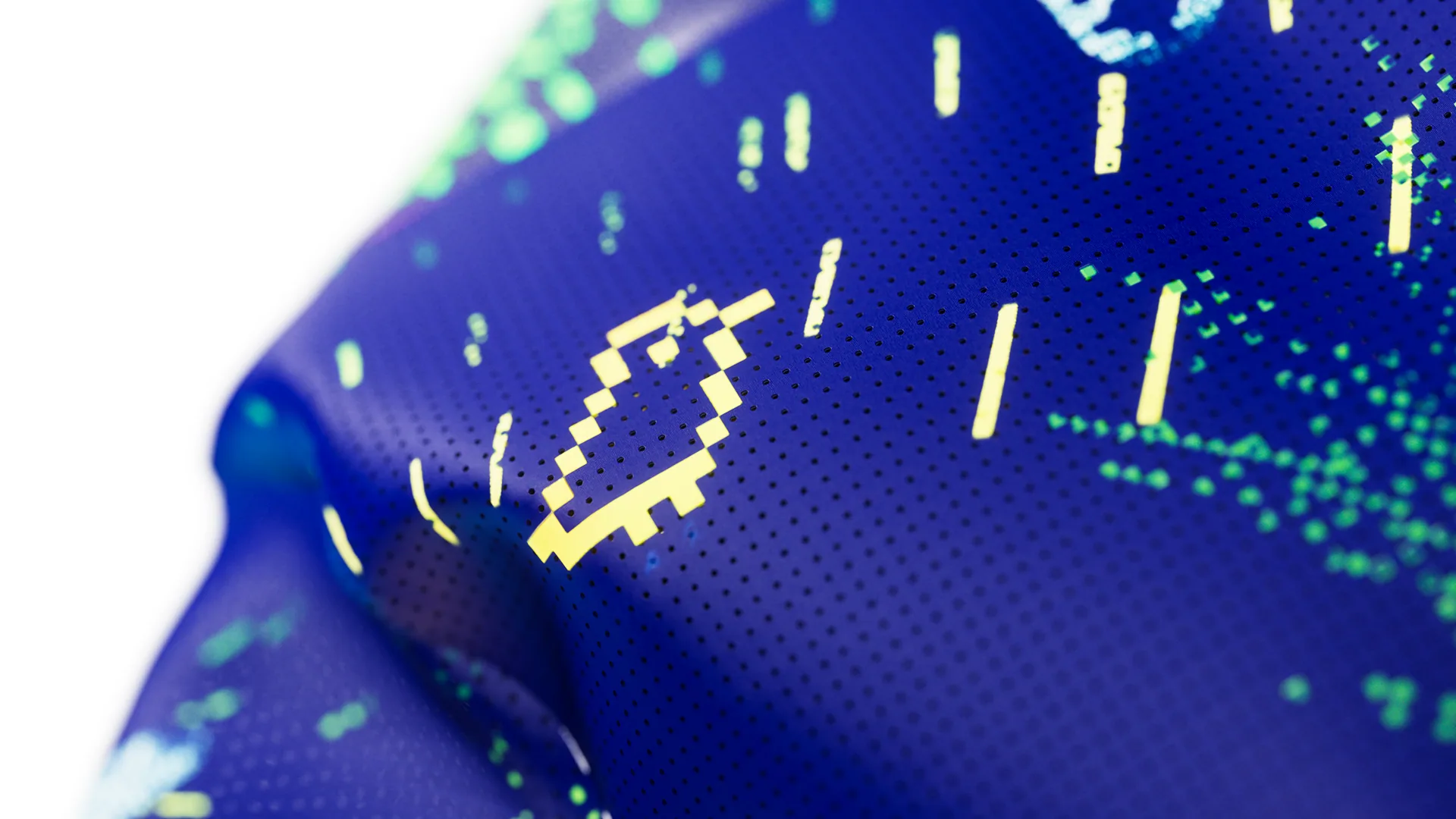 Extreme close up of the navy blue jersey fabric showing a pixelated yellow smiley face graphic and green dot pattern printed on a perforated textile surface